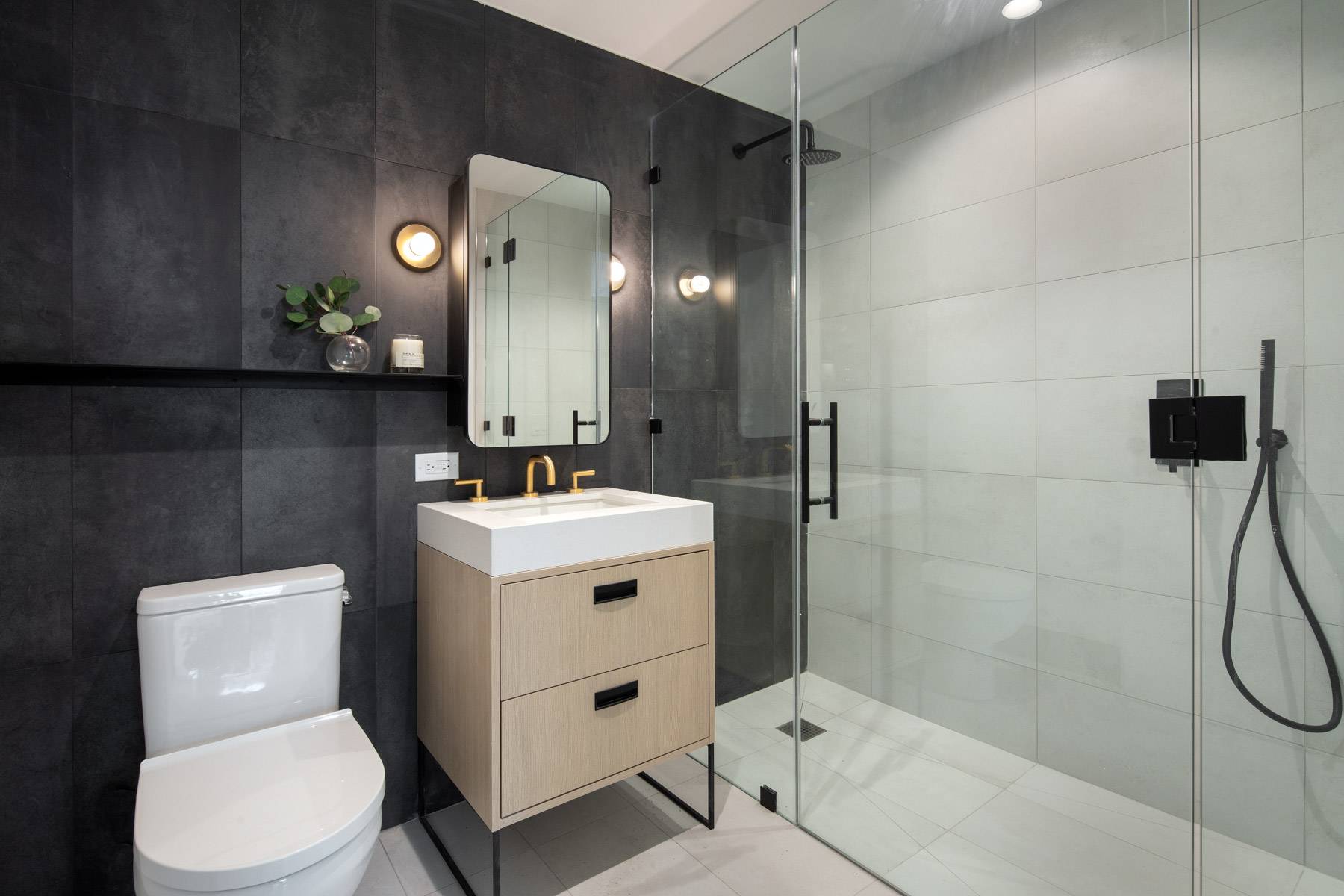 Primary bathroom with titled walls throughout, dark and light tiles and standing shower