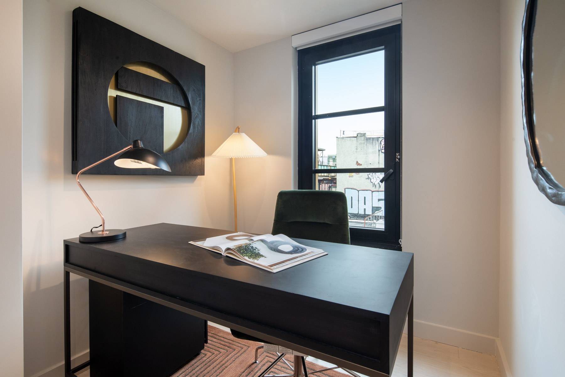 Home office with desk, chair, window and modern mirrors on wall