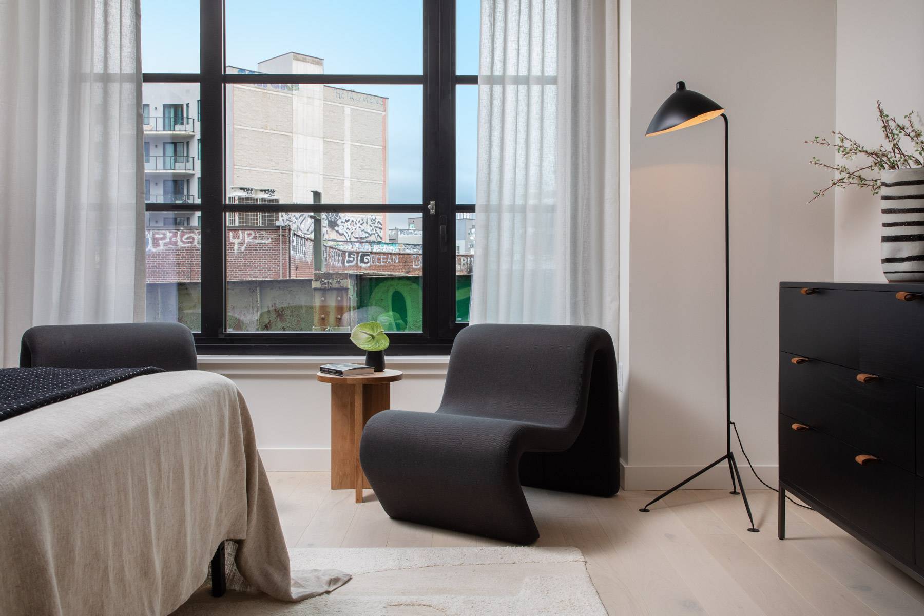 Studio bedroom detail showing seating, lamp, window and dresser