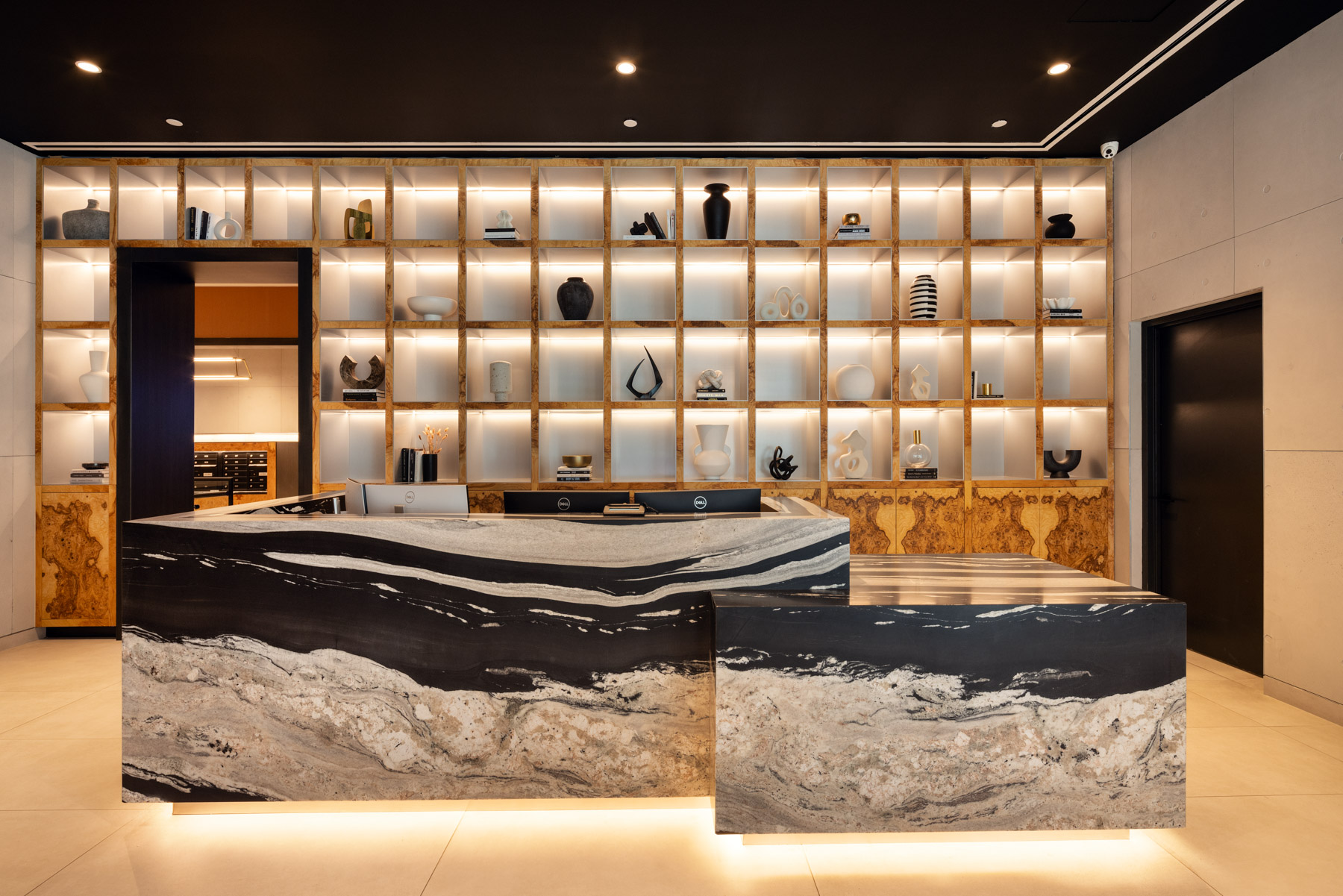 Modern lobby with unique desk and grid shelving with contemporary sculptures